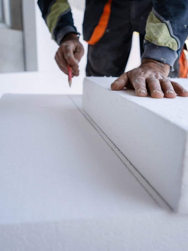 Worker use pen to mark the correct length and dimension of styrofoam during the wall insulation process at the construction site to cut the right size of the board